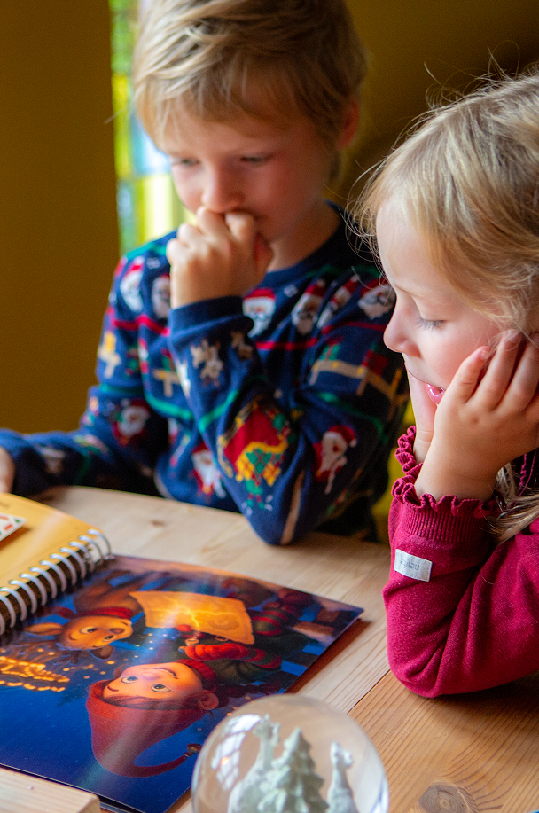 Et close up billede af far og søn som sidder og læser en julehistorie fra Julemandes Posthus