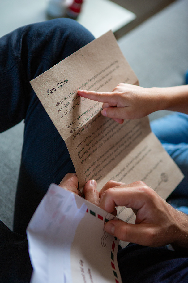 Et close up billede af far og søn som sidder og læser en julehistorie fra Julemandes Posthus