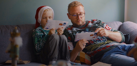 Et close up billede af far og søn som sidder og læser en julehistorie fra Julemandes Posthus